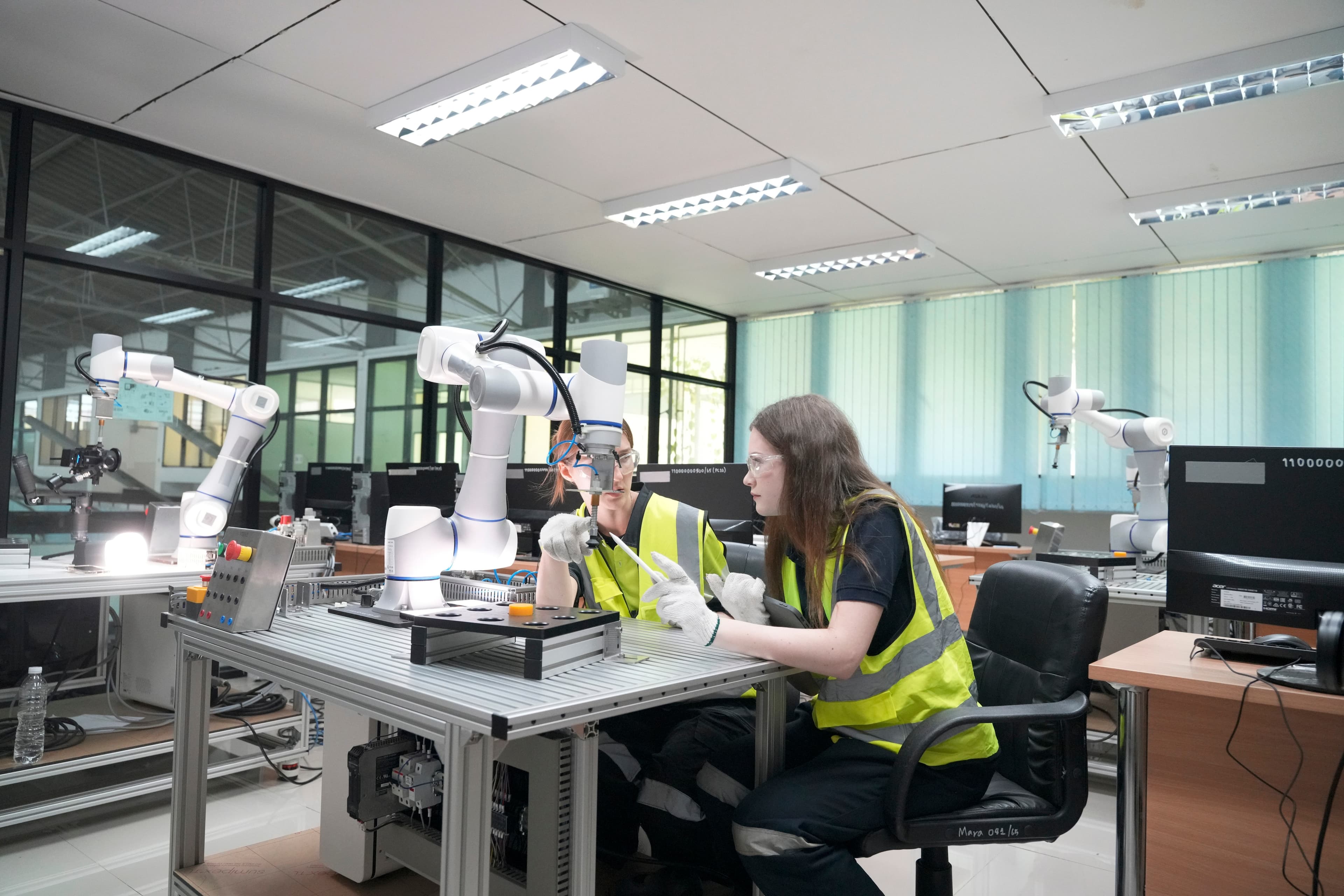 Engineers working alongside advanced robotics in a modern factory setting, representing QReserve’s capability to coordinate complex scheduling, enforce safety certifications, and track downtime for automated manufacturing assets.